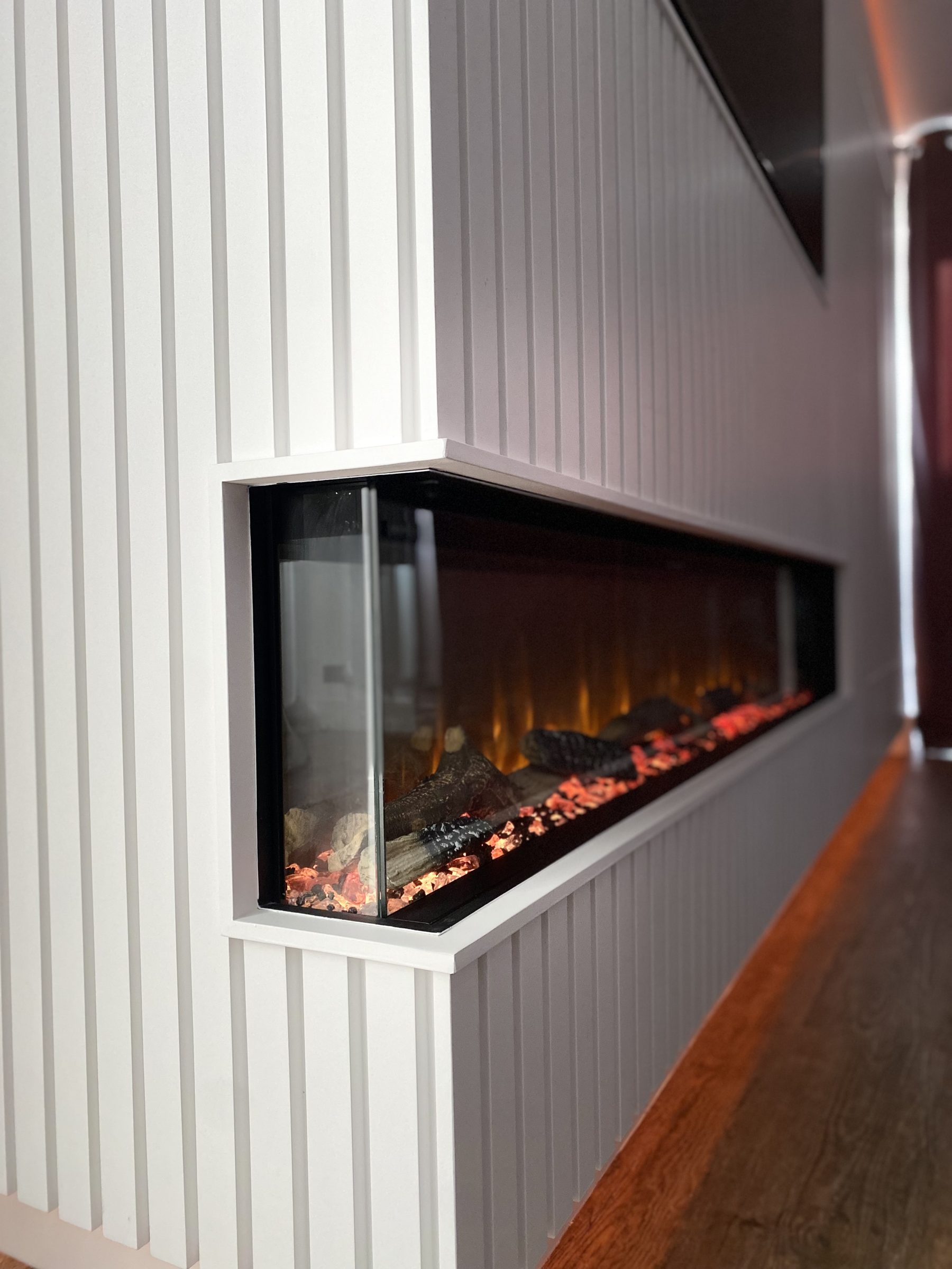 Slatted panelled media wall with an inset landscape electric fire, made by VIP Walls