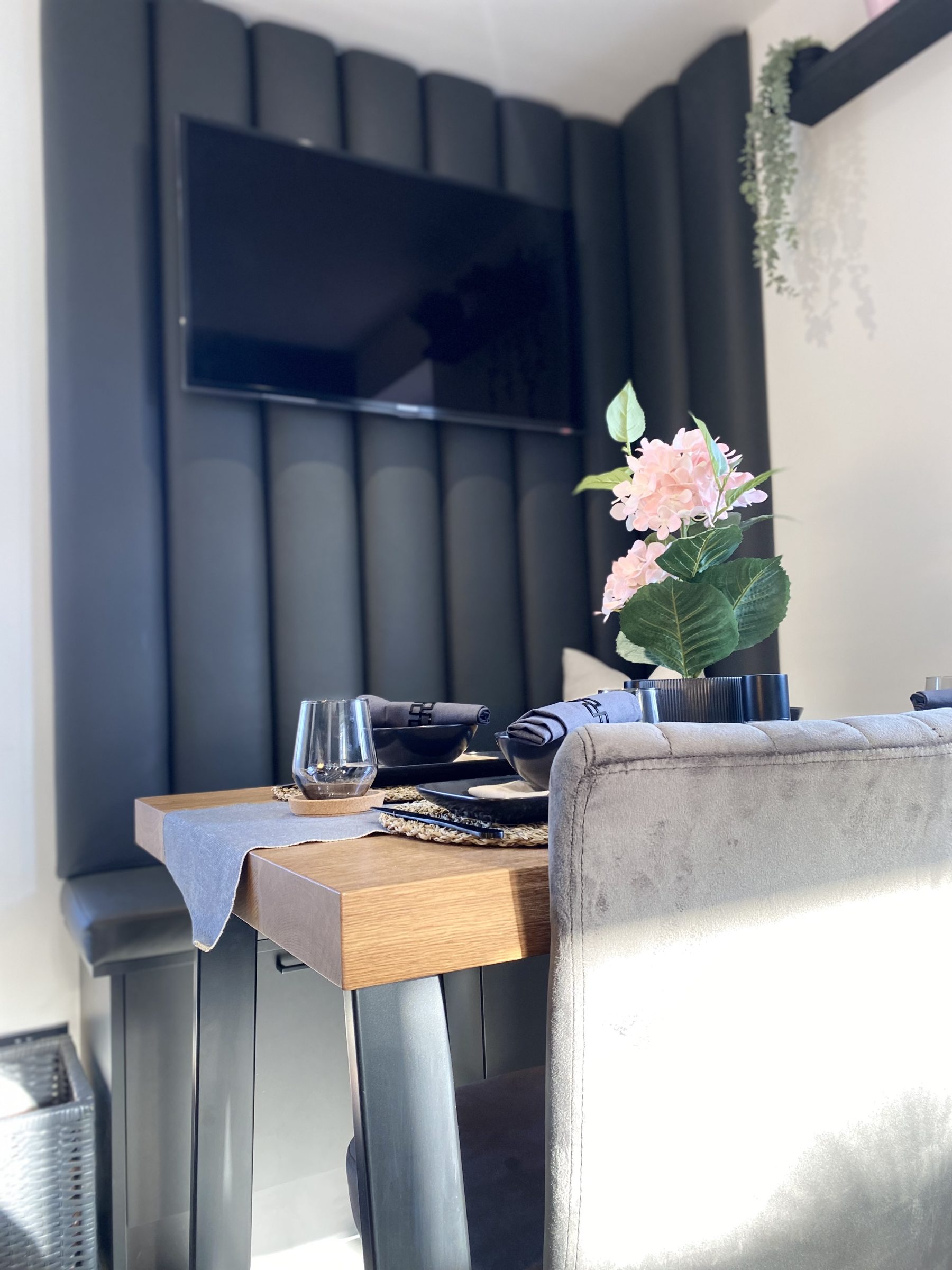 Vertically panelled wall with a wall-mounted television above a dining table