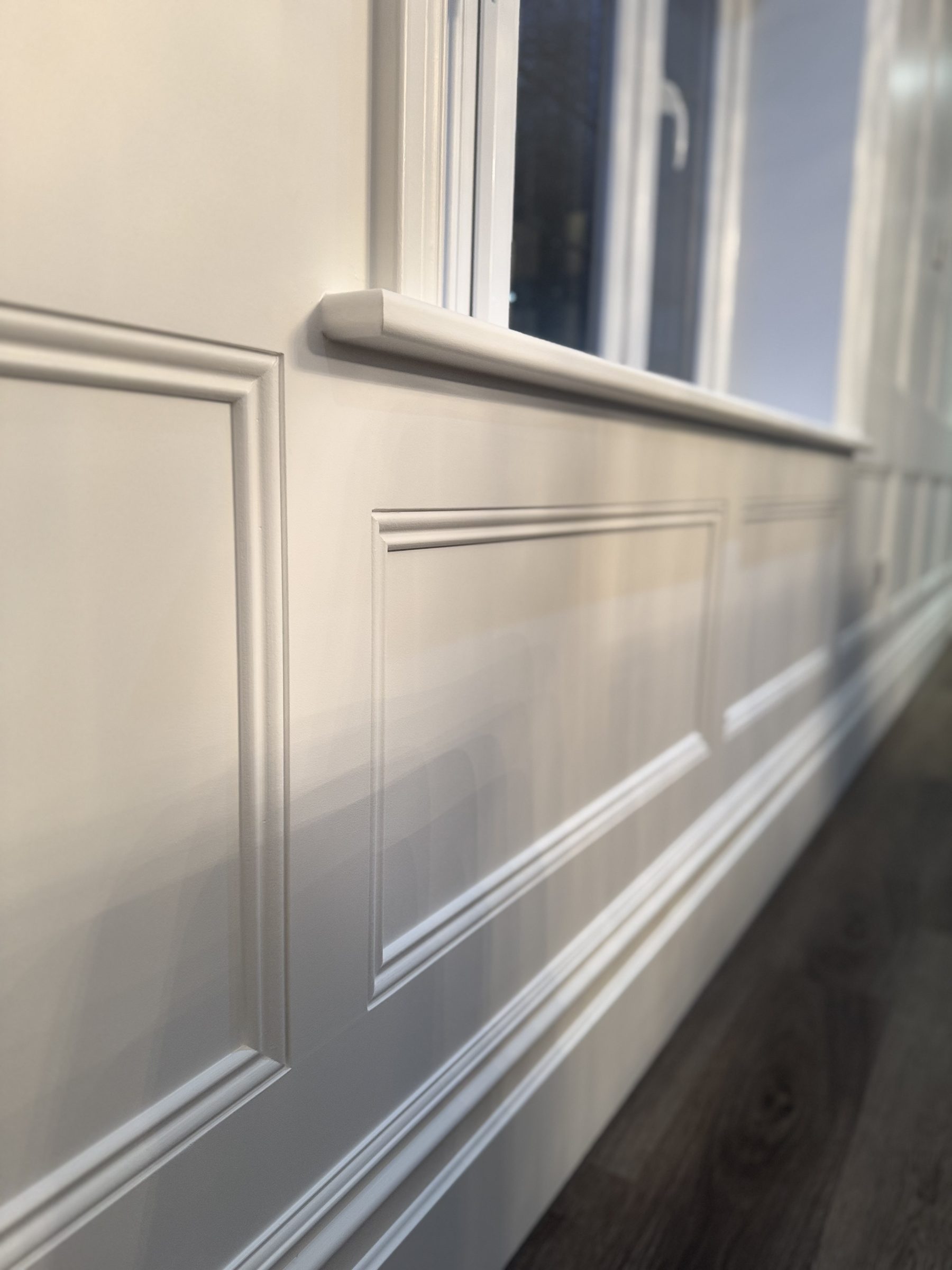 Painted panelling running beneath a window with a moulded rail