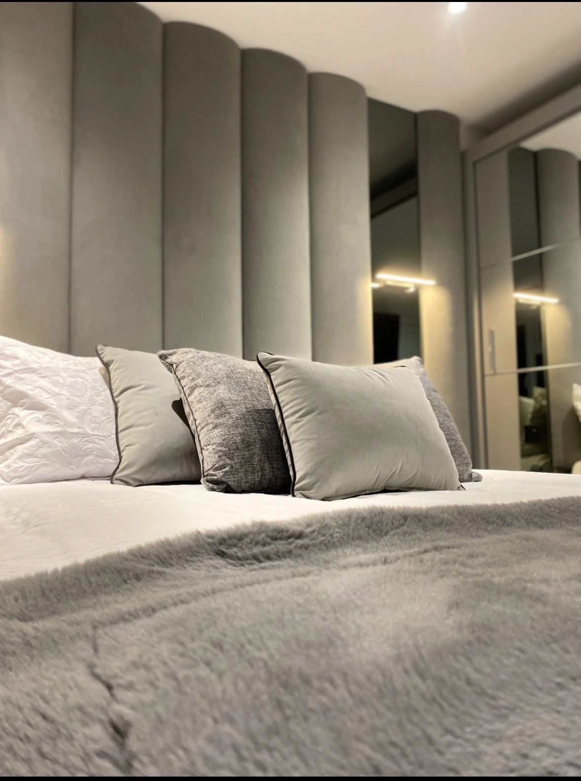 Upholstered feature wall and headboard behind a bed, made by VIP Walls